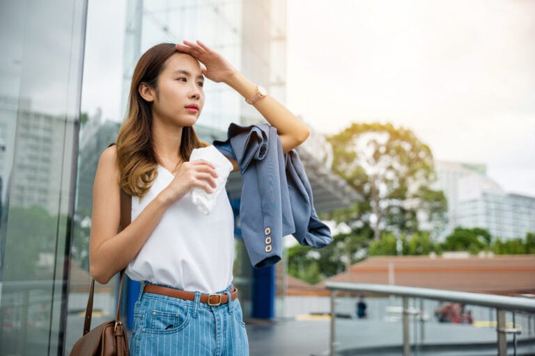 Asian beautiful business woman drying sweat her face with cloth in warm summer day hot weather
