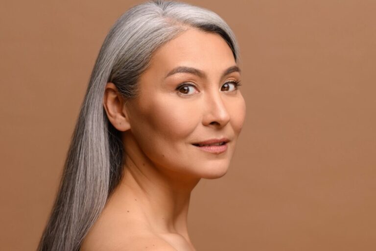 Headshot beautiful middle-aged Asian woman with fresh clean healthy skin isolated on beige Headshot beautiful middle-aged Asian woman with fresh clean healthy skin isolated on beige
